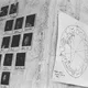 An einer Wand kleben Polaroid-Fotos mit handschriftlichen Namen und Begriffen sowie ein astrologisches Horoskop mit dem Namen „Franz Kafka“ und Geburtsdaten. Die Szene wirkt kreativ und persönlich dokumentiert.