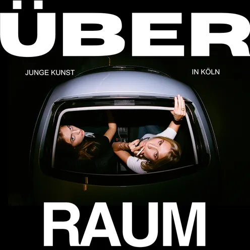 Zwei junge Frauen blicken durch das offene Schiebedach eines Autos nach oben. Umrahmt wird das Bild von großem, weißem Text: „ÜBER RAUM – Junge Kunst in Köln“. Die Szene wirkt urban, provokant und künstlerisch inszeniert.