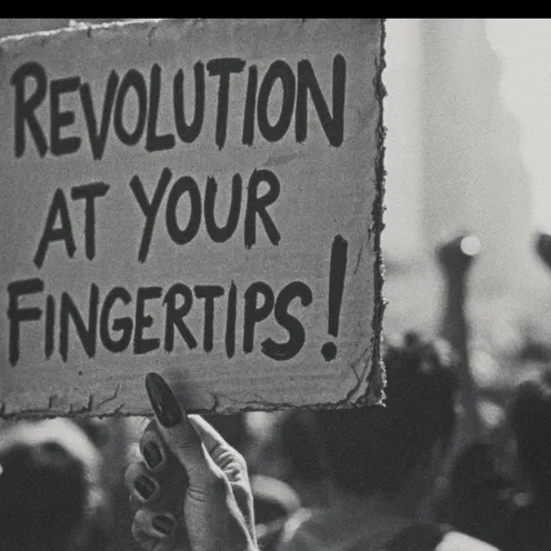 Schwarzweißfoto einer Demonstration: Eine Frau mit heller Haut hält mit lackierten Fingernägeln ein Pappschild hoch. Darauf steht „Revolution at your fingertips!“. Im Hintergrund stehen mehrere Personen verschiedener Geschlechter; ihre Arme mit erhobenen Fäusten ragen aus der Menge.