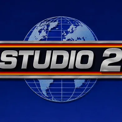 Silberner 3D-Schriftzug „STUDIO 2“ auf schwarzem Balken mit rot-goldenen Streifen. Im Hintergrund eine stilisierte Weltkugel mit Kontinenten und Gitternetzlinien auf tiefblauem Grund. Das Logo wirkt metallisch, markant und dreidimensional.