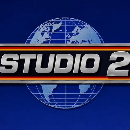 Silberner 3D-Schriftzug „STUDIO 2“ auf schwarzem Balken mit rot-goldenen Streifen. Im Hintergrund eine stilisierte Weltkugel mit Kontinenten und Gitternetzlinien auf tiefblauem Grund. Das Logo wirkt metallisch, markant und dreidimensional.